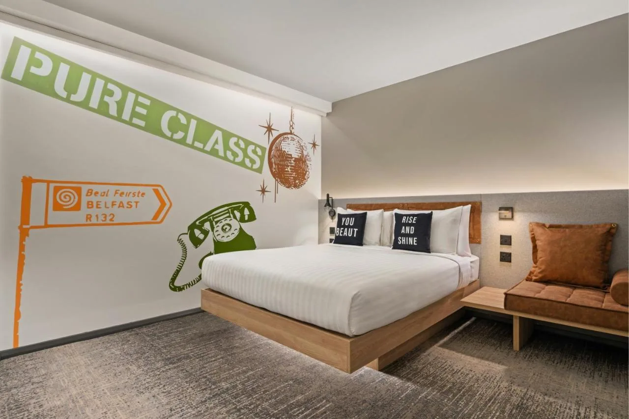 a bedroom with a king sized bed and a couch at Moxy Belfast City in Belfast