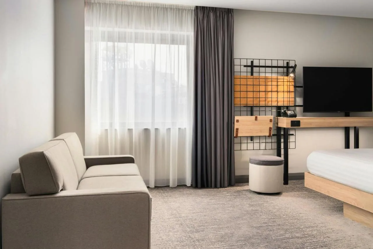 a bedroom with a bed and a couch and a tv at Moxy Belfast City in Belfast