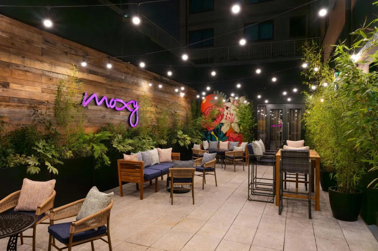 a restaurant with tables and chairs and plants at Moxy Belfast City in Belfast