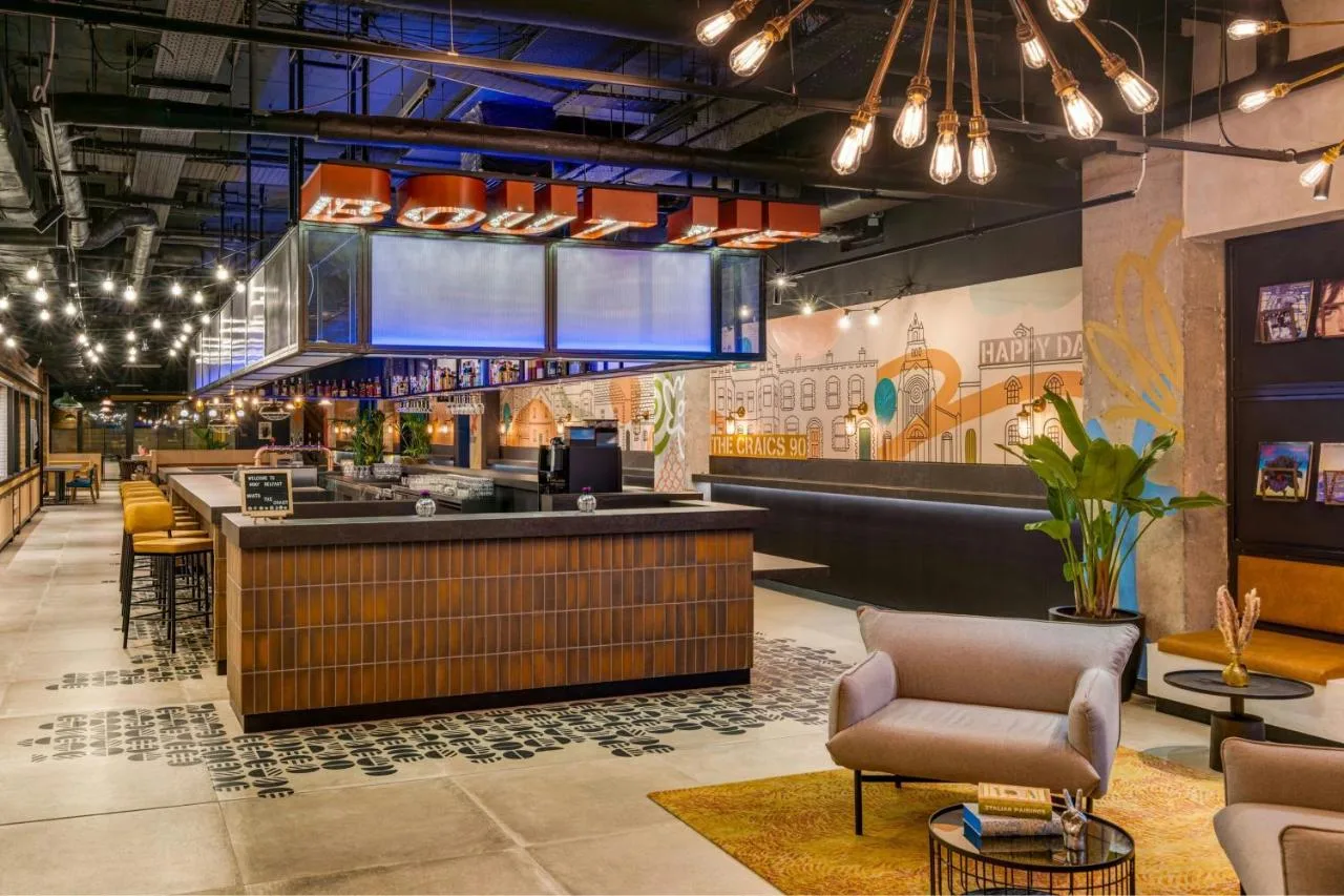 a restaurant lobby with a bar and chairs at Moxy Belfast City in Belfast